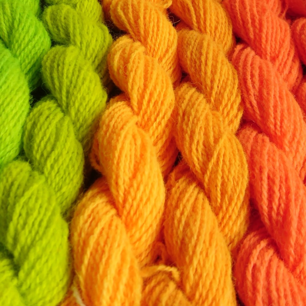 Photo of neon dyed yarn skeins in a rainbow layout